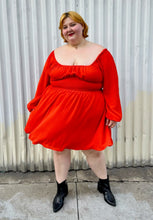 Load image into Gallery viewer, Additional full-body front view of a size 2X WRAY red-orange scoop neck mini dress with smocked waist and puff sleeve with elastic cuff styled with black boots on a size 22/24 model.
