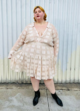 Load image into Gallery viewer, Full-body front view of a size 26 ASOS cream colored square pattern sheer mesh tiered button-up shirt dress with cream lining styled with black boots on a size 22/24 model. The photo is taken outside in natural lighting.
