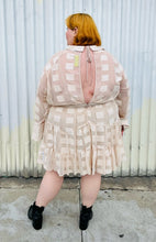 Load image into Gallery viewer, Full-body back view of a size 26 ASOS cream colored square pattern sheer mesh tiered button-up shirt dress with cream lining styled with black boots on a size 22/24 model. The photo is taken outside in natural lighting.
