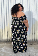 Load image into Gallery viewer, Full-body back view of a size 2X Forever 21 black, white, and yellow daisy pattern smocked bust off-shoulder maxi dress with high-low tulip hem styled with black combat boots on a size 24/26 model. The photo is taken outside in natural lighting.
