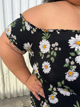 Load image into Gallery viewer, Close up view of the smocked bust off-shoulder detail of a size 2X Forever 21 black, white, and yellow daisy pattern smocked bust off-shoulder maxi dress with high-low tulip hem styled with black combat boots on a size 24/26 model. The photo is taken outside in natural lighting.
