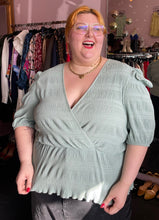 Load image into Gallery viewer, Front-side view of a size 24 ASOS sea foam green faux wrap textured babydoll blouse styled with black denim on a size 22/24 model.

