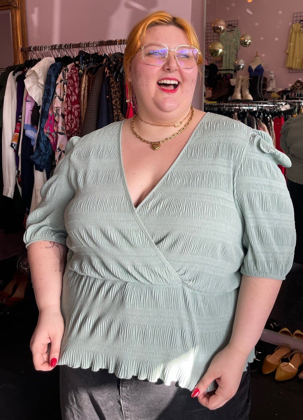Front-side view of a size 24 ASOS sea foam green faux wrap textured babydoll blouse styled with black denim on a size 22/24 model.