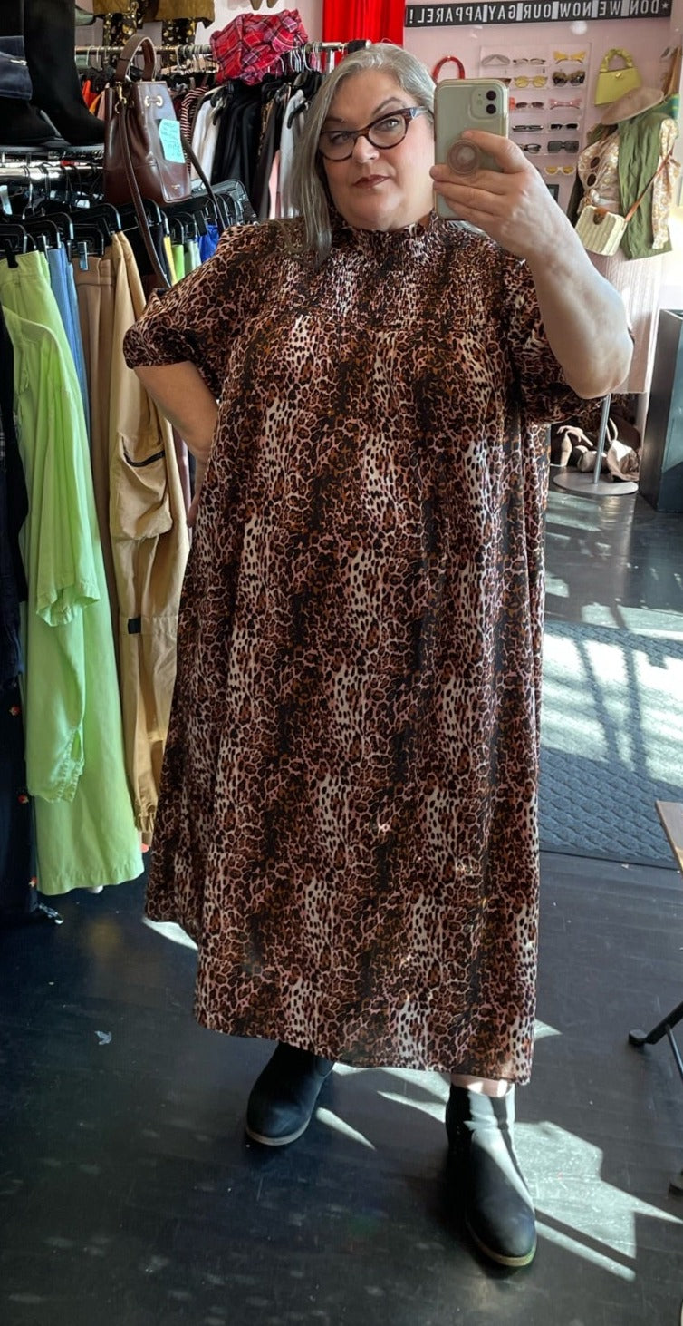Full-body front view of a size 26 Wednesday's Girl by ASOS pink, brown, white, and black leopard pattern high-neck maxi dress with smocking at the neck styled with black boots on a size 20/22 model.