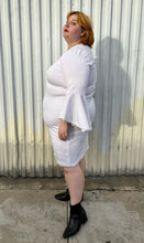 Load image into Gallery viewer, Full-body side view of a size 24 Eloquii white shift dress with long bell sleeves styled with black pointy boots on a size 22/24 model. The photo is taken outside in natural lighting.
