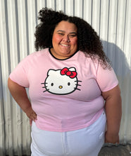 Load image into Gallery viewer, Front view of a size 5XL SHEIN x Hello Kitty baby pink tee with Hello Kitty graphic and black piping at the neckline styled with white denim on a size 24/26 model.
