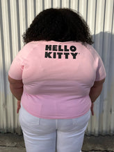 Load image into Gallery viewer, Back view of a size 5XL SHEIN x Hello Kitty baby pink tee with Hello Kitty graphic and black piping at the neckline styled with white denim on a size 24/26 model.
