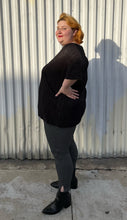 Load image into Gallery viewer, Full-body side view of a size 24 ASOS black plisse pleated tee styled over black and white windowpane pattern pants with black point boots on a size 22/24 model. The photo is taken outside in natural lighting.
