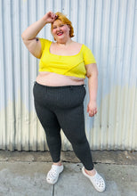 Load image into Gallery viewer, Full-body front view of a size XXL Urban Outfitters size XXL (fits up to 20/22) lemon yellow exposed seam detail crop top with cap sleeves styled with black and white windowpane plaid pants and white crocs on a size 22/24 model. The photo is taken outside in natural lighting.
