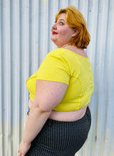 Load image into Gallery viewer, Side view of a size XXL Urban Outfitters size XXL (fits up to 20/22) lemon yellow exposed seam detail crop top with cap sleeves styled with black and white windowpane plaid pants on a size 22/24 model. The photo is taken outside in natural lighting.
