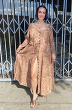 Load image into Gallery viewer, Full-body front view showing off the slit of a size 12 Mara Hoffman tan, brown, and white snake print button-up maxi dress with hip pocket details styled with snake print heels on a size 10 model. The photo is taken outside in natural lighting.
