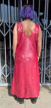 Load image into Gallery viewer, Full-body back view of a size 14 Dima Ayaad grapefruit pink colored v-neck gown with big sequins all throughout styled with black combat boots on a size 10 model. The photo is taken outside in natural lighting.
