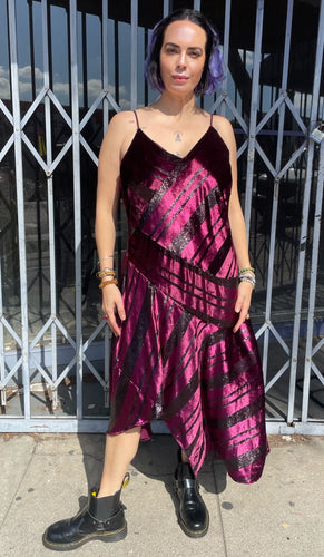Full-body front view of a size 12 Parker NY for 11 Honoré maroon-purple velvet shift midi dress with asymmertical handkerchief hemline styled with combat boots on a size 10 model. The photo is taken outside in natural light.
