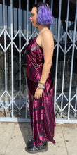 Load image into Gallery viewer, Full-body side view of a size 12 Parker NY for 11 Honoré maroon-purple velvet shift midi dress with asymmertical handkerchief hemline styled with combat boots on a size 10 model. The photo is taken outside in natural light.
