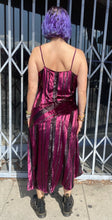 Load image into Gallery viewer, Full-body back view of a size 12 Parker NY for 11 Honoré maroon-purple velvet shift midi dress with asymmertical handkerchief hemline styled with combat boots on a size 10 model. The photo is taken outside in natural light.

