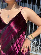 Load image into Gallery viewer, Close-up view of the maroon-purple velvet material of a size 12 Parker NY for 11 Honoré maroon-purple velvet shift midi dress with asymmertical handkerchief hemline. The photo is taken outside in natural lighting.
