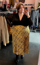 Load image into Gallery viewer, Full-body front view of a size 24 ASOS black v-neck baby doll top with sheer long sleeves styled tucked into a yellow and black maxi skirt with a brown beret and black boots on a size 24 model. The photo is taken inside in overhead lighting.
