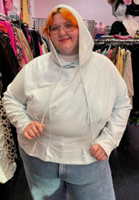 Load image into Gallery viewer, Front view of a size 4X Fabletics pastel blue darted and flared hem hoodie styled with the hood up over a pair of lightwash jeans on a size 22/24 model.
