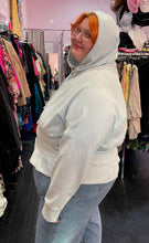Load image into Gallery viewer, Side view of a size 4X Fabletics pastel blue darted and flared hem hoodie styled with the hood up over a pair of lightwash jeans on a size 22/24 model.
