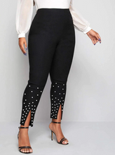Load image into Gallery viewer, Three-quarter view of a pair of black leggings with white beading at the lower leg and front slits.
