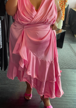 Load image into Gallery viewer, Closer front view of a size 4 Fashion to Figure x Garner Style collab bubblegum pink maxi wrap dress with big ruffle tiers and a wicker-style buckle belt styled without its belt on a size 22/24 model.
