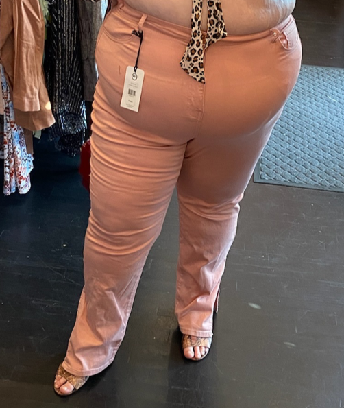 Closer front view of a pair of size 24 Fashion to Figure peach-pink straight leg denim styled with snakeprint heels on a size 24 model.