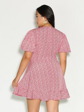 Load image into Gallery viewer, Back view of a Bloomchic red and white ditsy floral mini dress with a ruffled hem.
