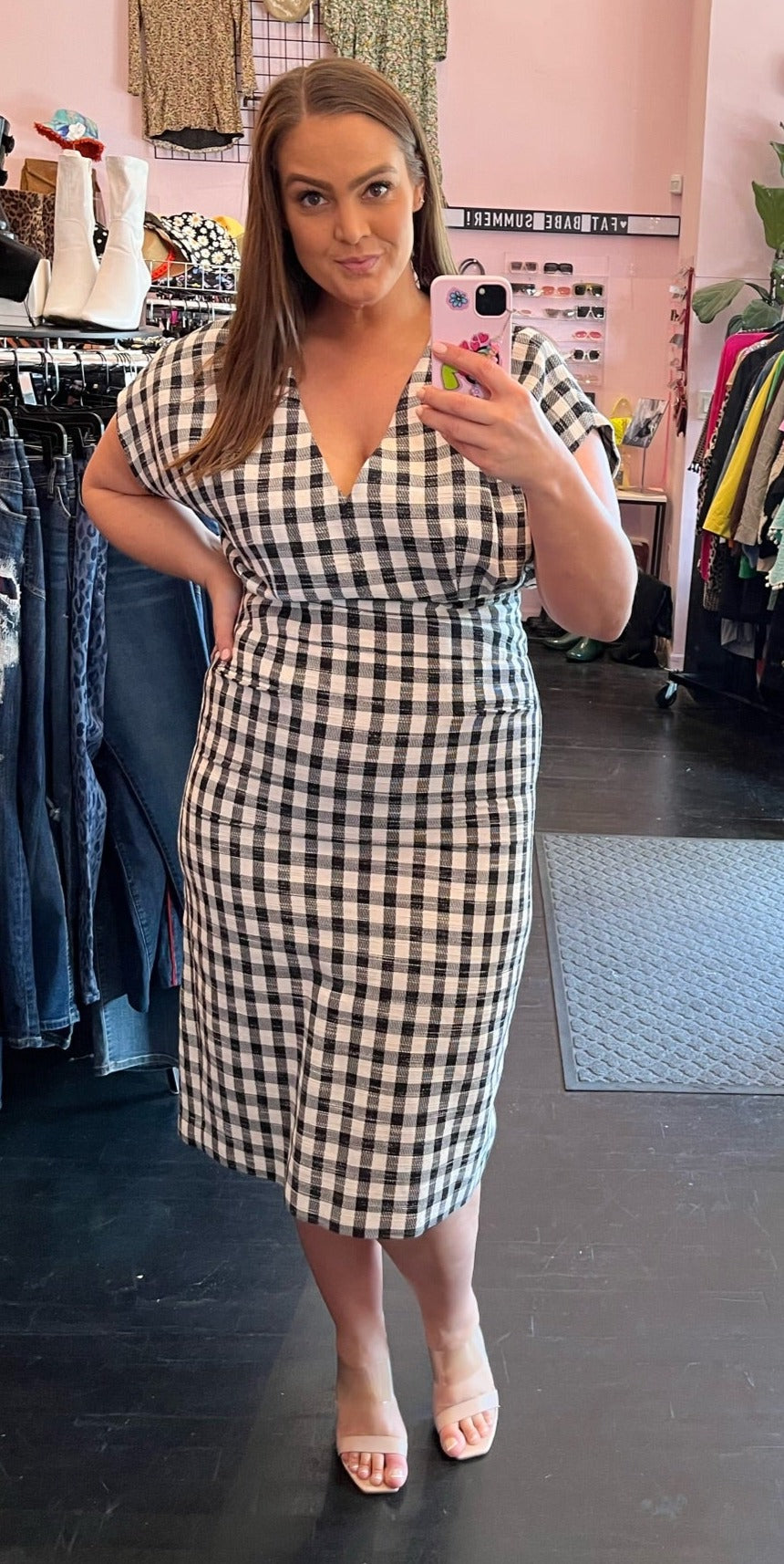 Full-body front view of a size 16 Derek Lam drop-shoulder v-neck black and white gingham midi dress styled with nude heels on a size 16 model. The photo is taken inside under flourescent lighting.