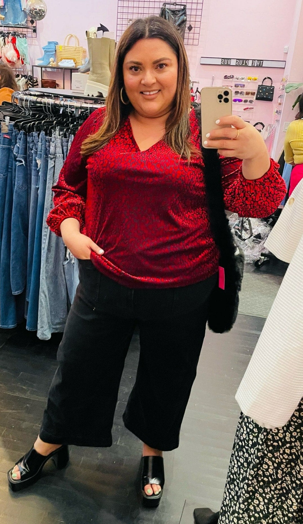 Full-body front view of a size 3X JM Collection red and black velvet animal print v-neck blouse styled with black pants on a size 18/20 model.